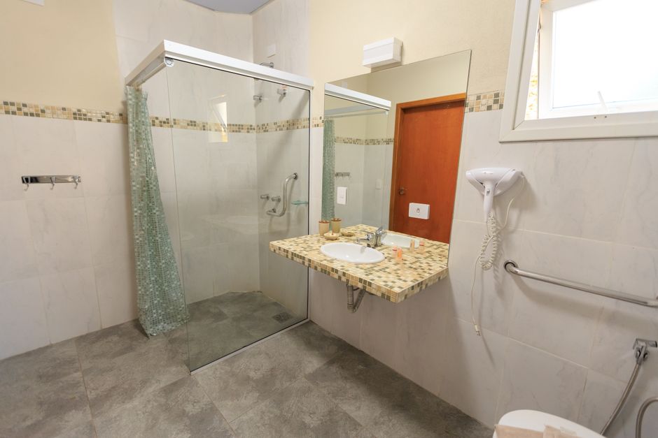 Salle de bain accessible avec douche de plain-pied, barres d'appui et vasque adaptée